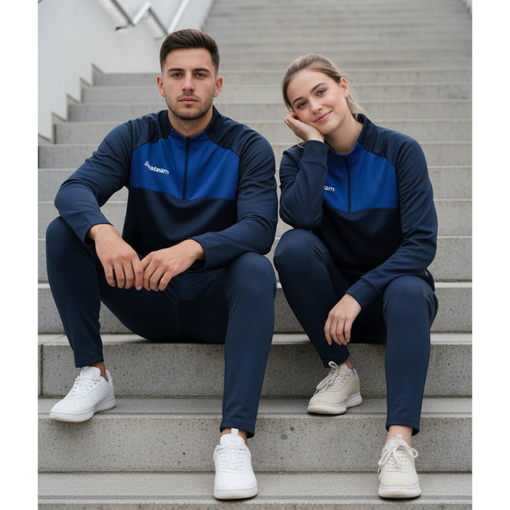 Two people wearing matching blue and navy tracksuits sitting on a staircase.